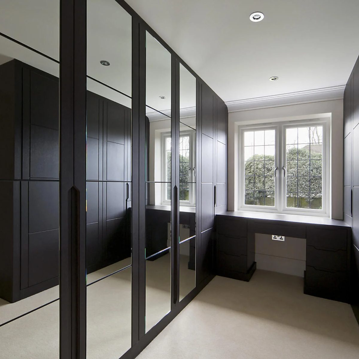 Inloop kledingkast met meerdere kleine spiegels voor een ruimtelijk effect.