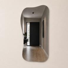 Organische spiegel Demi met asymmetrische vorm en randloos design in een modern interieur.