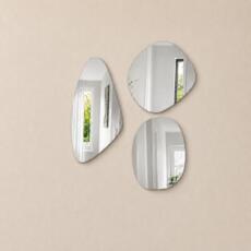 Organische spiegelset van drie verzilverde spiegels in verschillende vormen op een beige wand.