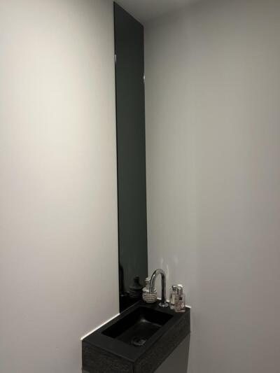 Gekleurde spiegel in het grijs. Geplakt aan de muur in het toilet