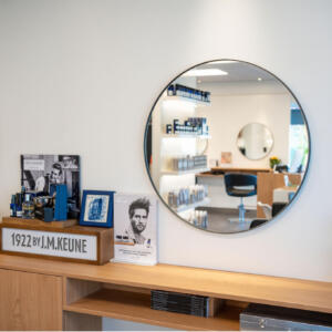 Een ronde spiegel op maat bevestigd aan de muur van een kapsalon